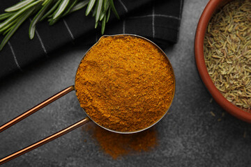 Scoop with curry powder on brown table, flat lay