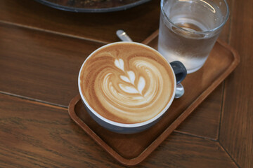 Coffee latte on wooden table in the breakfast morning. Warm, light atmosphere. Relaxing in a coffee shop.