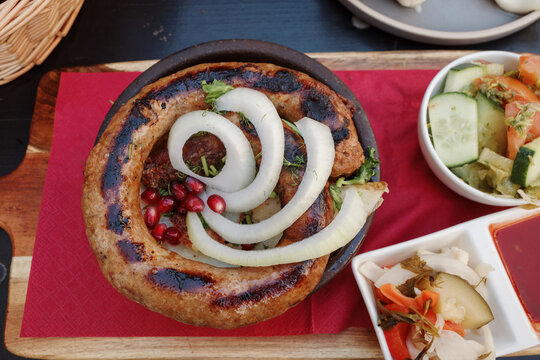 Top view, curl of Kupati,  Georgian spicy sausage with distinct flavor, on top with onion and barberry.
