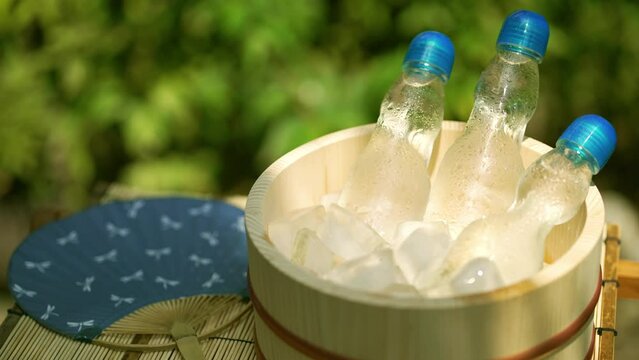 揺れる木漏れ日と木桶で冷える瓶ラムネ / 夏休み・昭和レトロ・日本の夏の風物詩イメージ