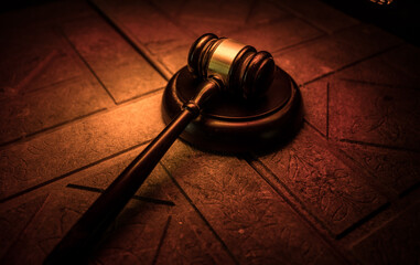 Law theme, mallet of the judge on wooden desk. Law gavel on dark foggy background with light.