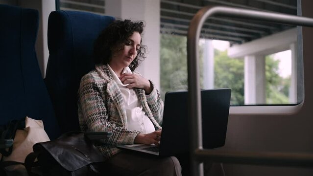 pregnant woman working on a laptop in a train