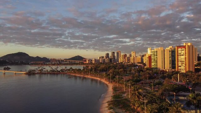 Vista a&eacute;rea de drone de um amanhecer na Praia do Canto, Vit&oacute;ria, Esp&iacute;rito Santo, Brasil, captando pessoas usando uma canoa havaiana.