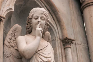 Keuken foto achterwand Vrijheidsbeeld religious statue figure of an angel making silence on a grave in an outdoor cemetery