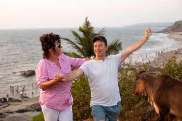 Happy tourist lifting arm up while female camper smiling, holding male hand. Mature couple spending...