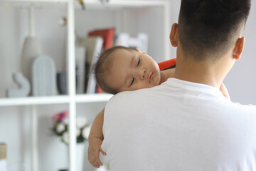 Cute sleepy new born baby over his fathers shoulders. Fatherhood and loving care concept