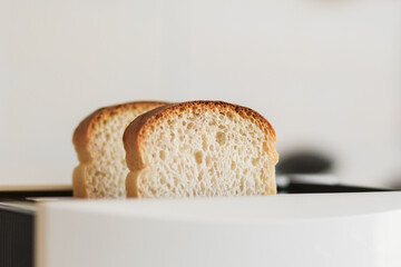 Sliced fresh bread inserted into a white toaster, selective soft focus.