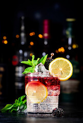Bramble alcohol cocktail drink with dry gin, liqueur, syrup, lemon juice, blackberry and ice. Black...