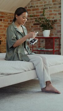 A young pregnant woman smiles while looking at ultrasound pictures while sitting on the bed at home