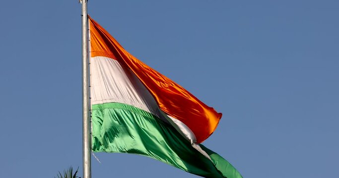 Close up view of shiny Indian flag against blue sky background