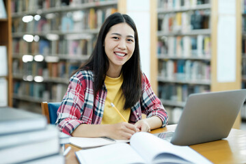 Portrait of a Smart Beautiful Asian Girl Studing and Reading Text Books Smiling Looking at Camera.