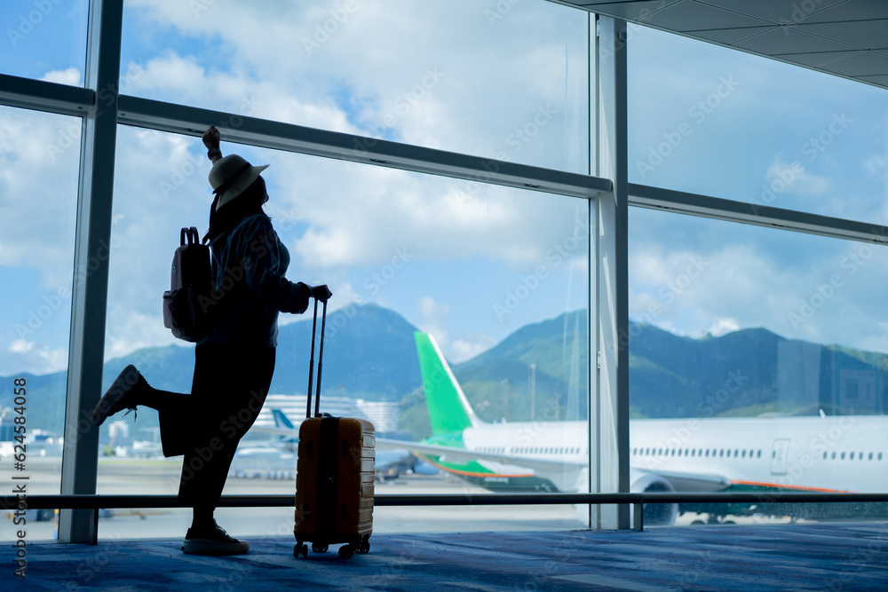 Wall mural young woman traveler looking at the airplane at the airport, travel concept