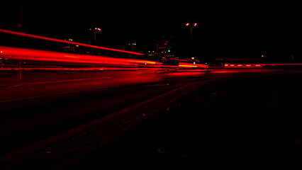 Lights of cars at night. Street line lights. Night highway city. Long exposure photograph night road. Colored bands of red light trails on the road. Background wallpaper defocused photo. 
