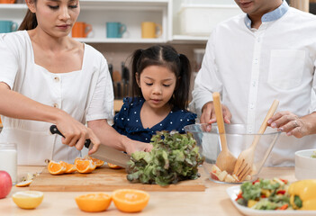 Asia kid girl cooking salad with family in kitchen at home