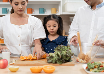 Asia kid girl cooking salad with family in kitchen at home