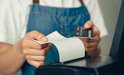 Customer holding credit card for payment on card reader machine to owner at restaurant.