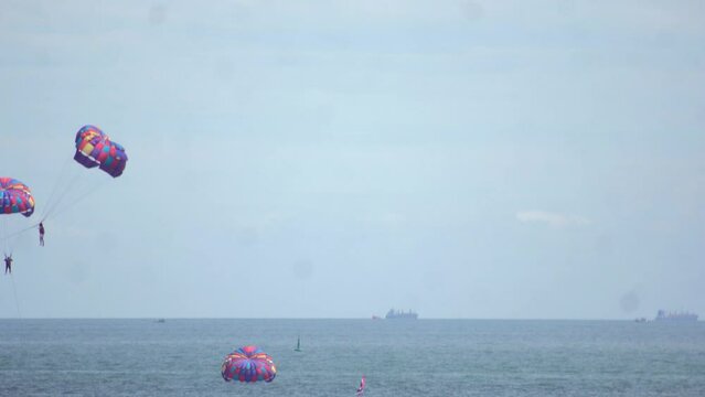 Time-lapse footage of people parasailing above the sea.