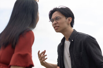 Am asian couple have a heated argument with each other while outside. Turmoil and crisis in a young relationship. Uncertainty and conflict.