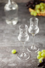 Grape vodka or grappa. Strong alcoholic drink in grappa glasses on the table. Fresh grapes