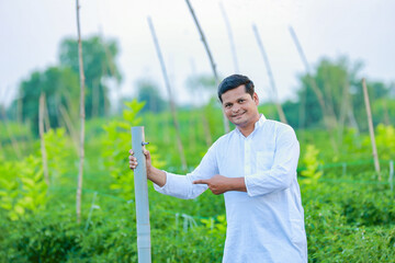 Happy Indian farmer, holding pipe in hand and looking camera