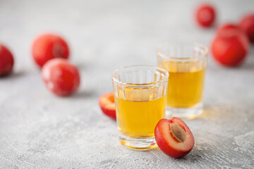 Plum brandy or plum vodka, strong drink in glasses on  table. Balkan Slivovica. Fresh red plums. Copy space