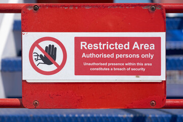 Warning Sign on a gate. Red and white restricted area sign, authorized persons only, with hand icon, on the deck of a ferry