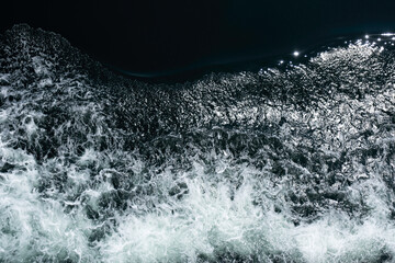 Bow waves of a ship with foam on the water of the sea. Splashing water. Top view