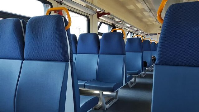 Empty commuter train car inside. Blue seats. Country trip, ordering tickets. Economy class. Simple video.