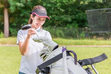 ゴルフ場でゴルフバッグにドライバーを入れる女性ゴルファー
