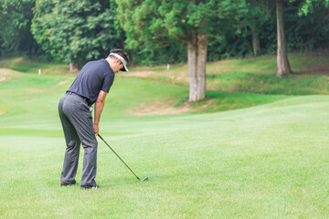 ゴルフ場でアイアンショットをするゴルファーの男性
