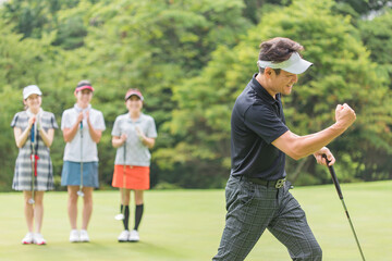 ゴルフ場のグリーンでゴルフをするゴルファーの男女(パター)
