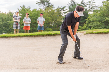 バンカーからゴルフボールを出すゴルファーの男性（バンカーショット）
