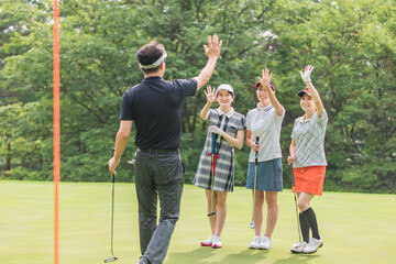 ゴルフ場のグリーンでゴルフをするゴルファーの男女(パター)
