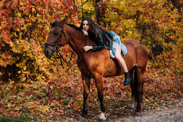 Beautiful young woman posing on a horse in a beautiful autumn forest