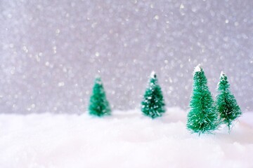 Christmas home decoration with Little handmade gift box in a snow covered miniature evergreen forest and bokeh light for copy space.