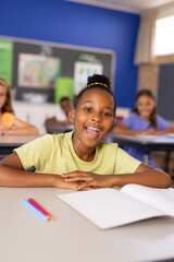 Portrait of happy african american schoolgirl in diverse elementary school class