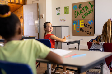 Obraz premium Portrait of happy caucasian schoolgirl in diverse elementary school class