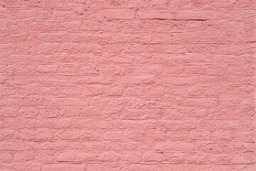 Texture of a brick wall coated with the thick layer of pastel pink paint as a romantic architectural background