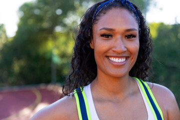 Portrait of happy biracial female basketball player wearing white blue tshirt at basketball court