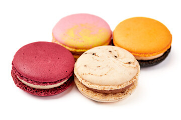 Obraz na płótnie Canvas Close up of 4 colorful macarons (pink, red, orange and cream-brown) isolated on white background.