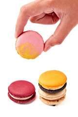 Hand holding pink macarons and 3 colorful macarons (orange , red and cream-brown) isolated on white background. Front side of macaron.