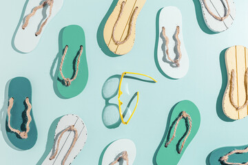 Summer minimal pattern, beach flip flops and sunglasses, vivid color flat lay, top view still life with woman slide sandals, many shoes, beach holiday concept, shadow from sunlight, summer vibes