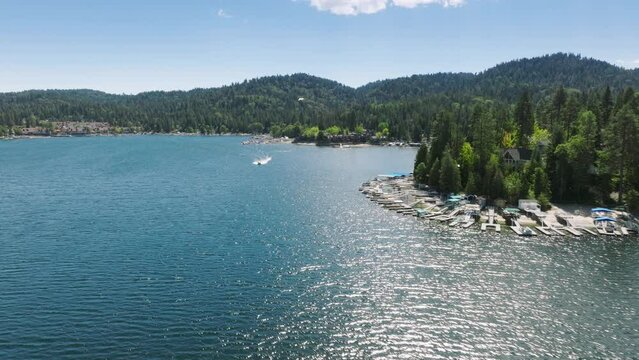 Distance shot of speedboat riding on water of Lake Arrowhead in San Bernardino Mountains, Los Angeles, California, USA. Aerial view of picturesque lake landscape surrounded green mountains, 4k footage