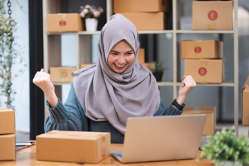 Muslim asian woman freelancer entrepreneur, Smile for sales success after checking order from online shopping store in a laptop at home office, Concept of merchant business online and eCommerce