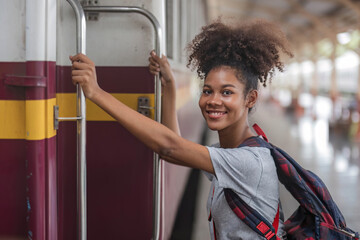 Traveler african asian american woman getting in a train to hop on train, Young woman female standing on train door peeking out looking from door, tourist on a train staion