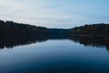 Stunningly beautiful lake in the golden autumn season. Magical multi-color reflection with light ripples on the surface of the water fall evening. Autumn scenery Colorful vibrant autumn forest with