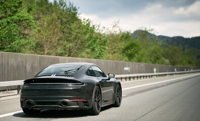 Sleek Black German Roadster. Brand New Luxury Carrera Sports Car on the Highway. Aerodynamic beast on the autobahn in Germany.