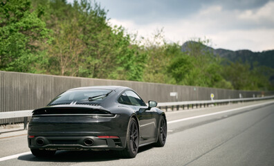 Sleek Black German Roadster. Brand New Luxury Carrera Sports Car on the Highway. Aerodynamic beast...