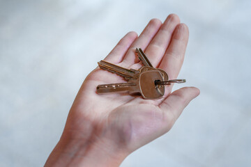 Pęk srebrnych kluczy do nowego mieszkania trzymany w dłoniach  - obrazy, fototapety, plakaty