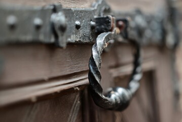 Ancient iron doorhandle on a wooden door as a closeup